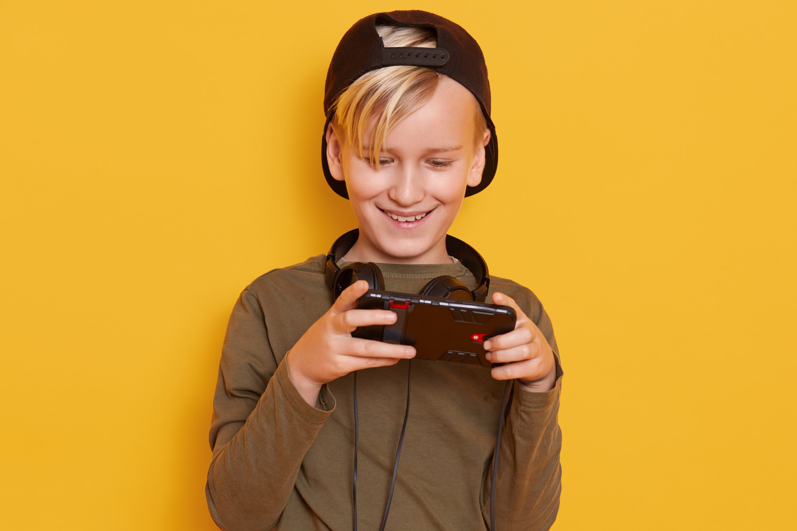 Horizontal Shot Little Boy Wearing Black Cap Green Hoody Posing With Cell Phone Hands Fashionable Kid Playing Online Games Scaled