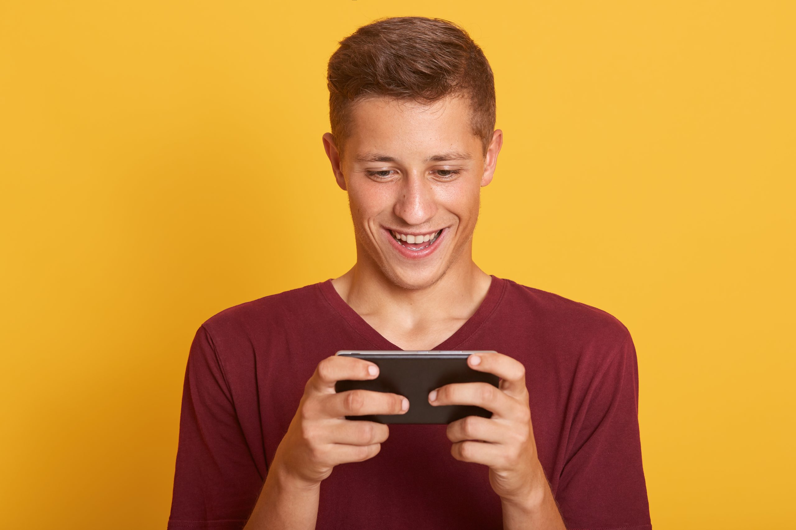 Smiling Young Man Playing Game Smartphone Looks Happy Concentrated Looking Smiling His Device S Screen Scaled